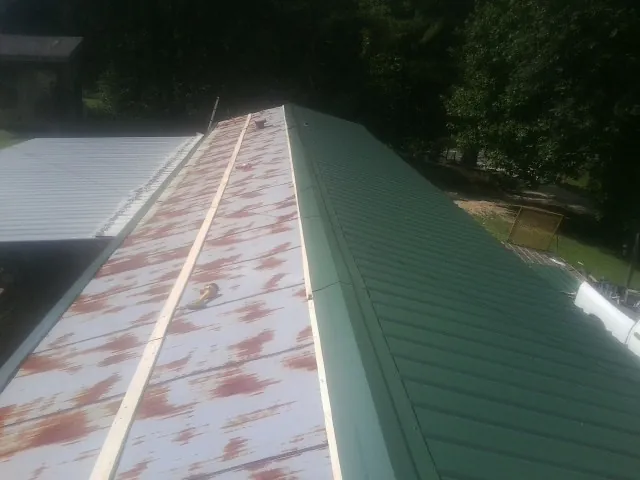 Old rusted panels beside newly installed green metal roofing — Wind Damage Roof Repair by Roofing Brothers in Grantham