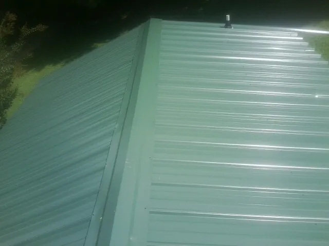 New green metal panels meeting at the ridge of a roof — Flat Roof Repair work by our crew in Grantham