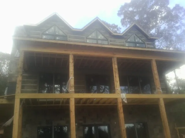 Dormers and porch framing on a large log home under construction — Roof Coating work by our crew in Grantham