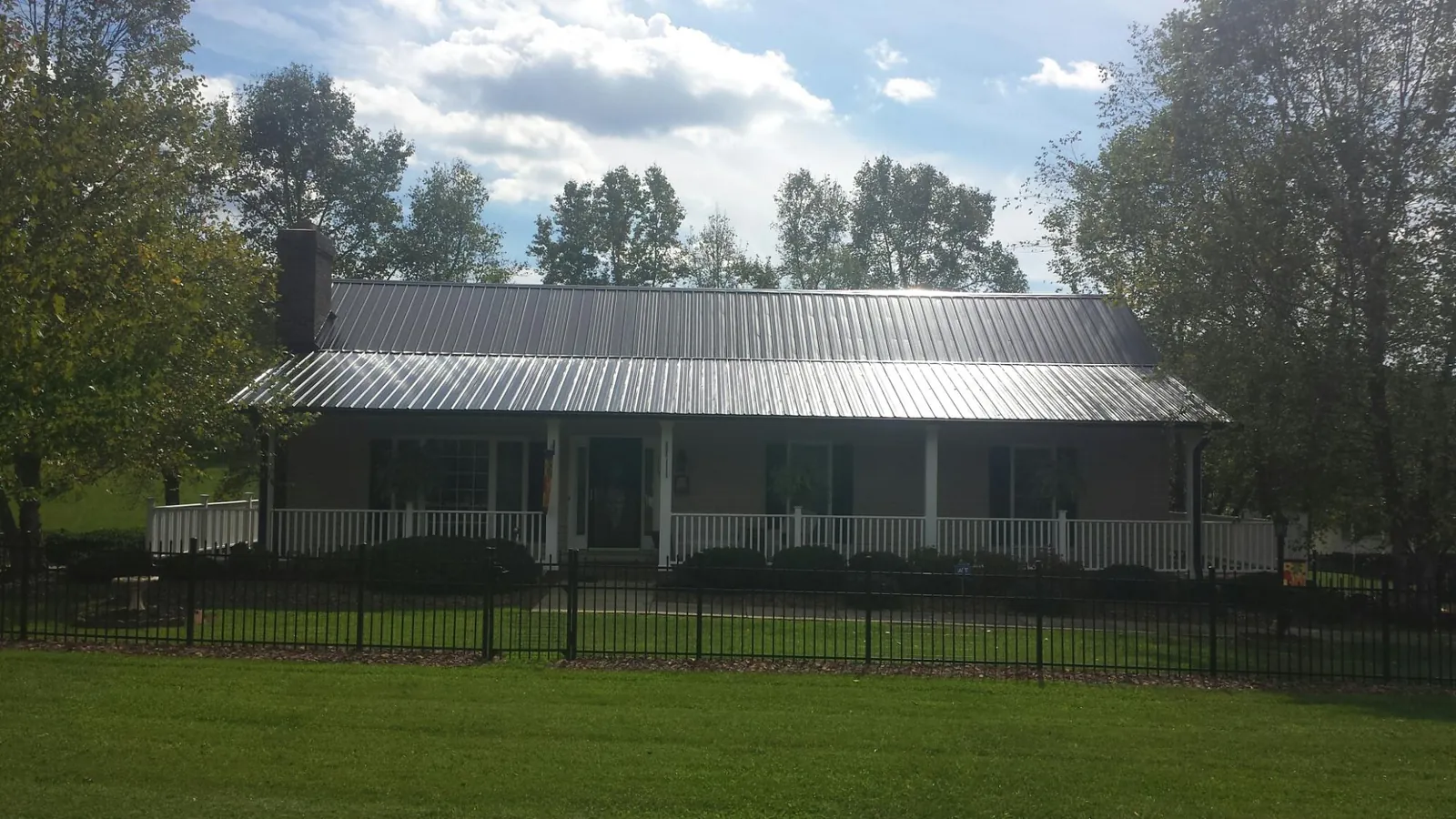 Gray metal roof on a brick ranch with a full width front porch — Gutter Guard Installation work by our crew in Grantham
